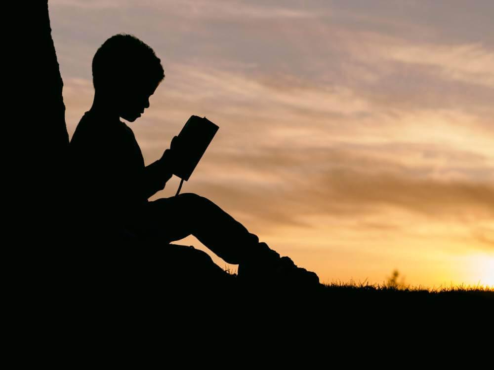 silhoutte of boy reading book