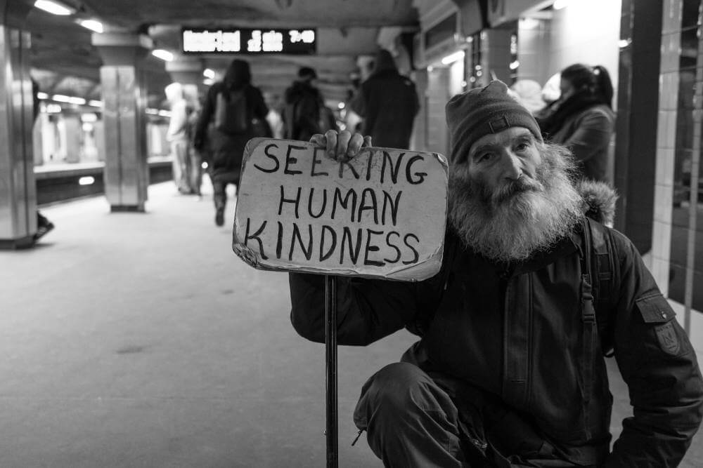 old person holding a sign seeking human kindness